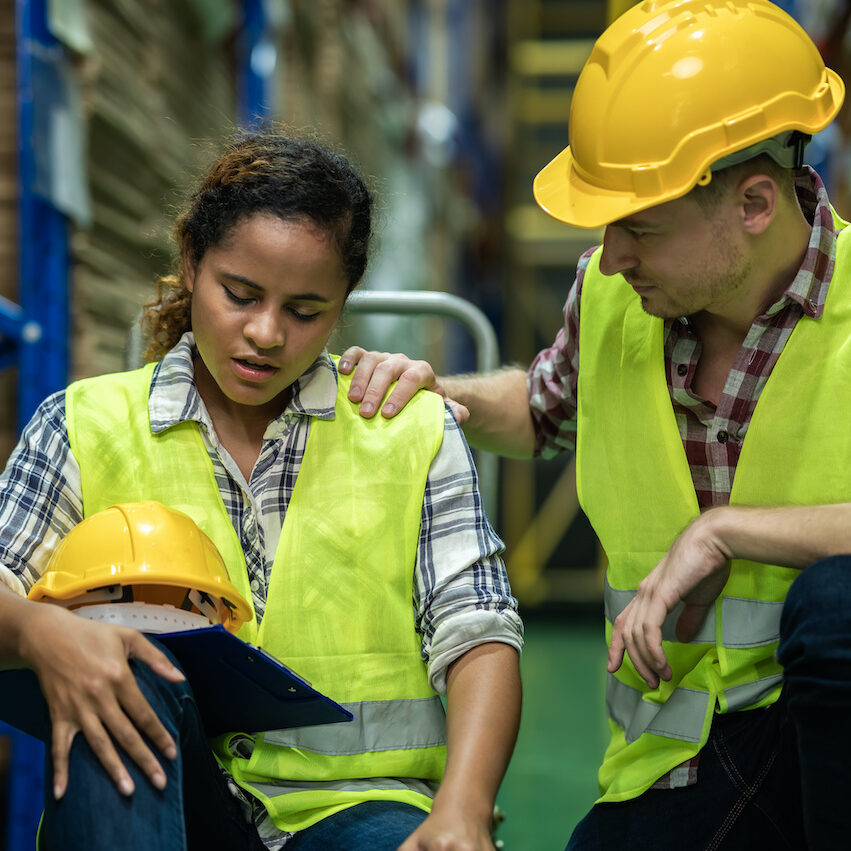 Young African female warehouse worker staff feeling sad and stress while Caucasian man consoling and encouraging due to been fired from job cause by company bankruptcy from coronavirus pandemic.